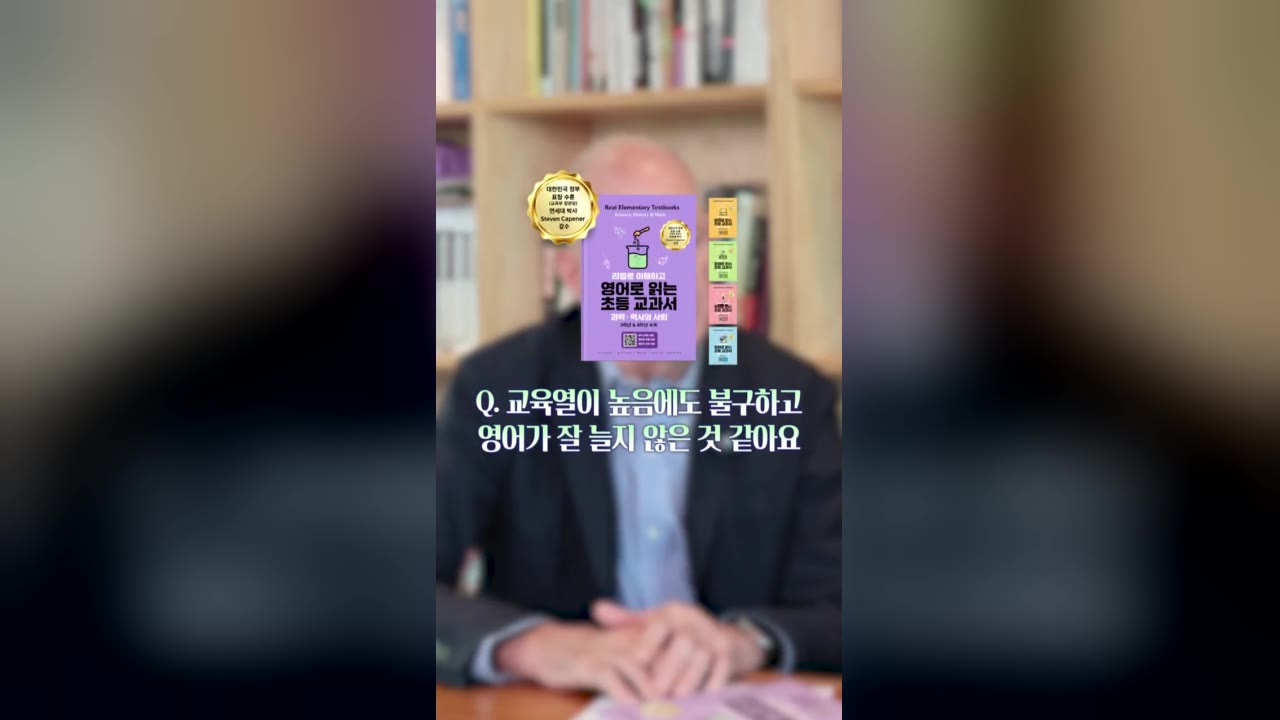 초등 영어 교재 숏폼 광고 사례 - 흐린 인터뷰 화면 위에 보라색 '영어로 읽는 초등 교과서' 표지와 'Q. 교육열이 높음에도 불구하고 영어가 잘 늘지 않은 것 같아요' 질문 자막이 놓인 세로 영상 첫 장면